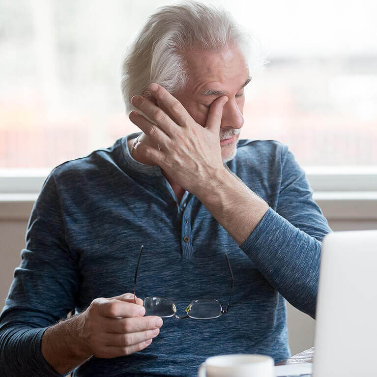 Older man rubbing his eye